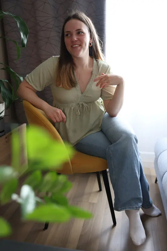 Doris Kelava sjedi u naslonjaču i smiješi se, s biljkom u prvom planu.